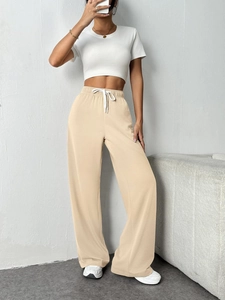 Close-up of elastic waistband with white drawstring on apricot wide-leg pants