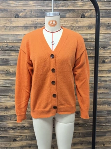 Detail of orange V-neck knit cardigan showing ribbed texture and brown buttons