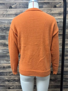 Detail view of the plain orange knit cardigan back featuring ribbed cuffs and hemline