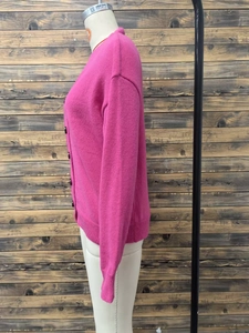 Detail of rose pink knit cardigan showing V-neck, buttons, and ribbed cuff texture