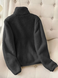 Détail de veste en polaire noire avec col montant sur un fond capitonné élégant