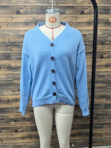 Detail view of light blue V-neck knit cardigan with five dark brown buttons on white mannequin