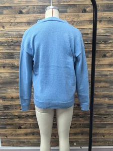 Detail view of the ribbed cuffs and hem on the back of this blue knitted cardigan