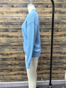 Detail of light blue knit cardigan with dropped shoulders and ribbed hem on mannequin