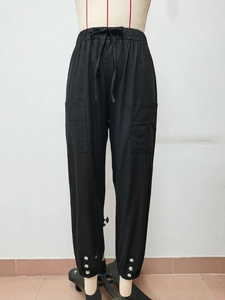 Dettaglio dei pantaloni larghi neri in cotone lino con vita elastica e polsini a bottone