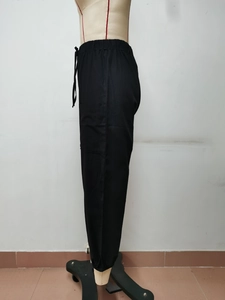 Dettaglio dei pantaloni cargo neri con vita elastica con coulisse e ampie tasche laterali