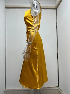Détail d'une robe de soirée en satin doré avec fente latérale et texture brillante métallique