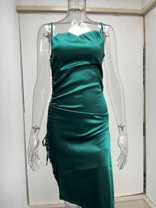 Détail d'une robe en satin vert foncé avec côtés froncés à cordon et texture soyeuse