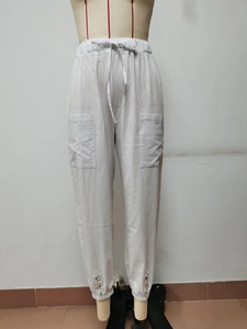 Dettaglio dei pantaloni in lino bianco con coulisse elastica e tasche a toppa laterali