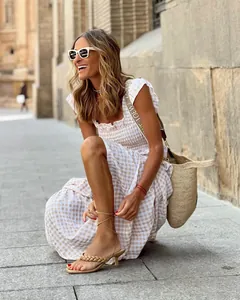 Detail of cream vichy plaid summer dress with pleated elastic waist and woven straw bag