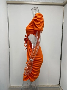 Dettaglio di un abito in maglia a coste arancione con tagli laterali e lacci