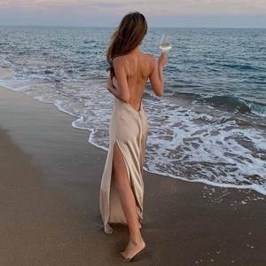Elegant champagne satin backless maxi dress with side slit against a sunset beach
