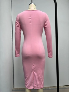 Dettaglio del retro di un abito rosa aderente in maglia con spacco sull'orlo