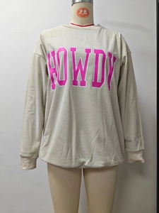 Détail de la texture velours côtelé avec lettrage rose Howdy sur sweat-shirt crème