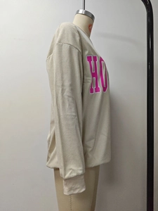 Détail d'un sweat-shirt côtelé beige clair avec grand imprimé de lettres roses