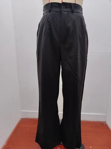 Detail showing high-waisted black wide-leg suit trousers with button closure and front pleats