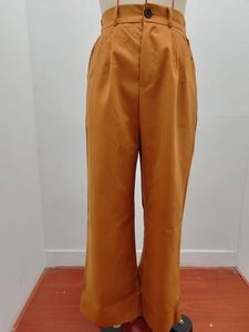 Close-up of high-waist trousers with black button closure and pleated front details