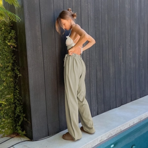 Detail of sage green high-waisted wide-leg pants with elastic drawstring waist and fluid drape