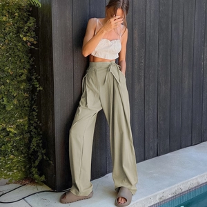 Detail of high-waisted olive wide-leg trousers with elegant waist tie and pleated texture
