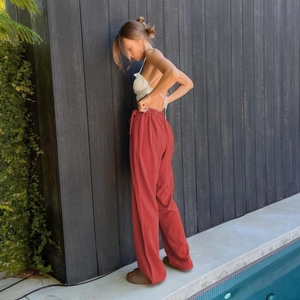 Detail view of high-waist loose wide-leg trousers in brick red with elastic waistband