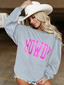Détail d'un sweat-shirt en velours côtelé gris clair avec lettrage Howdy rose et texture