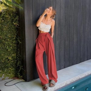 Detail of high-waist wide-leg trousers with tie waist and light pleated texture