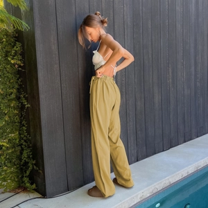 Detail of high-waisted mustard yellow wide-leg trousers with elastic drawstring waist
