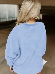 Détail d'un pull en maille côtelée bleu clair avec une coupe décontractée à col rond