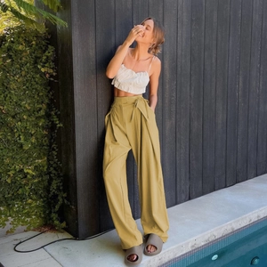 Detail of high waist mustard yellow wide leg pants with a matching waist tie belt