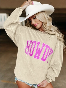 Détail d'un sweat en velours côtelé beige avec lettrage HOWDY rose et texture douce