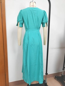 Detail of turquoise short-sleeved dress showing white buttons and fitted waist on mannequin