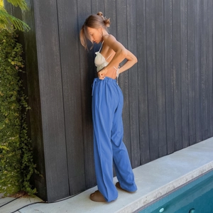 Detail view of high-waisted blue wide-leg trousers in flowing fabric with a summer drape