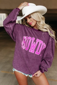 Détail d'un sweat en velours côtelé violet avec texte HOWDY blanc et bords roses