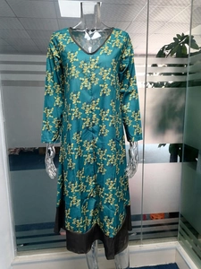 Détail du col en V et bordure marron sur robe mi-longue fleurie verte rétro