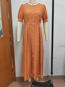 Detail of orange midi dress featuring white buttons and feminine puff sleeve design