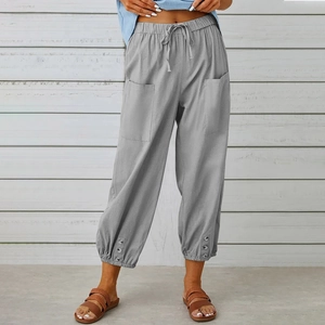 Dettaglio dei pantaloni grigi in lino con coulisse in vita e triplo bottone sull'orlo fondo