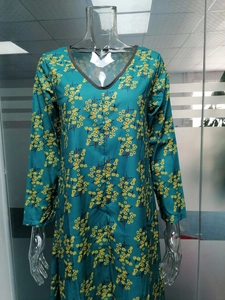 Détail de l'encolure en V d'une robe fleurie vert sarcelle sur un mannequin d'exposition