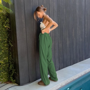 Outdoor view of dark green wide-leg pants with drawstring high waist and flowing drape