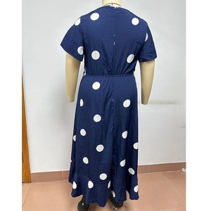 Dettaglio dell'orlo a balze e della fantasia a pois bianchi su un abito lungo blu navy