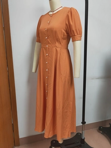 Detail of summer orange midi dress featuring white buttons and a slim high waist design