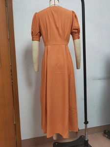 Detail of the back of a slim orange short-sleeved midi dress with buttoned cuffs