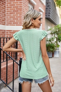 Détail d'un haut vert clair à manches courtes avec broderie anglaise et col en dentelle