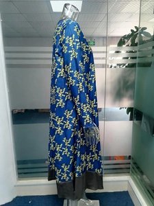 Détail d'une robe longue bleue à imprimé floral jaune avec un ourlet contrasté gris foncé
