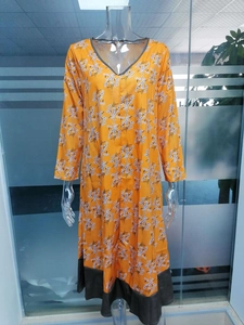 Détail de la robe florale orange vif avec col en V et finitions contrastées élégantes