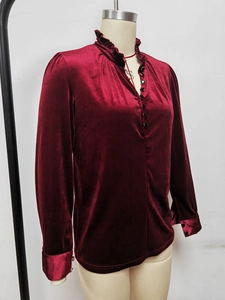 Détail de la chemise en velours bordeaux avec col à volants et boutons noirs élégants