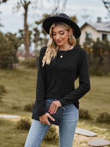 Close-up of black ribbed long sleeve knit top with elegant gold necklaces and accessories