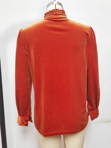 Détail du dos d'un chemisier en velours orange rouille avec col montant à volants