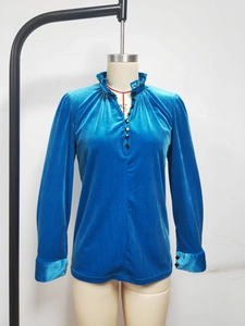 Détail du col en V à volants et boutons noirs sur une chemise en velours bleu