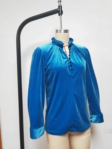 Détail du col volanté et des boutons sur une chemise en velours bleu foncé