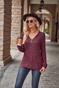 Dettaglio maglia a maniche lunghe bordeaux a costine con scollo a V e zip dorata
